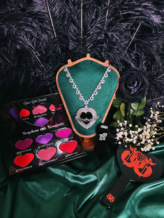 Makeup palette, necklace, and brush on a dark background